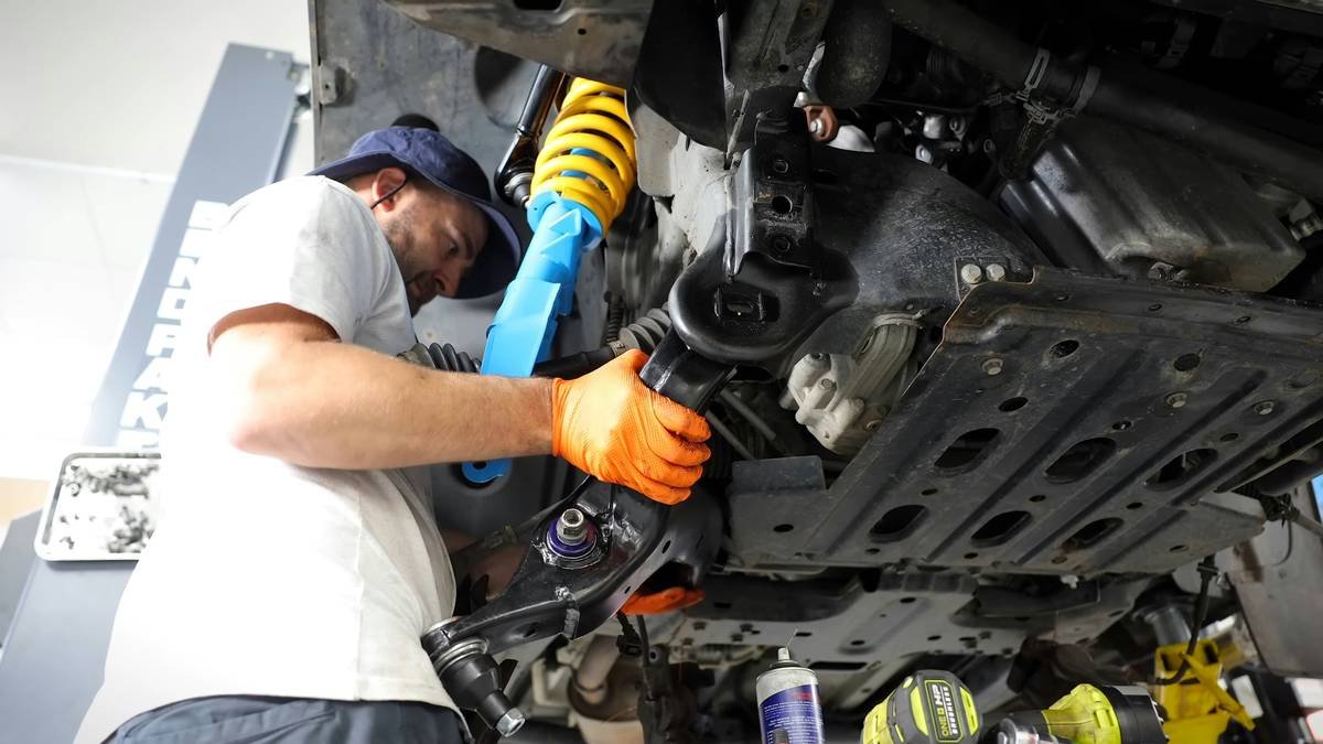 A mechanic working on a car's air conditioning system at a roadside service station.
